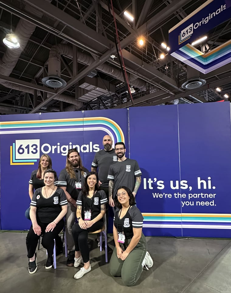 613 Originals employees posing in front of a banner wearing uniforms