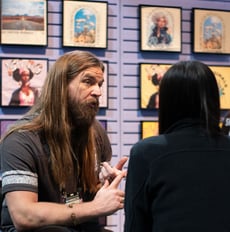 A man speaks to a person about all the benefits of transfers. Behind them is a wall of finished garments.